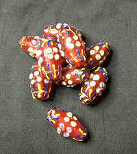 A pile of red glass beads, with mulitcoloured applied glass decorations